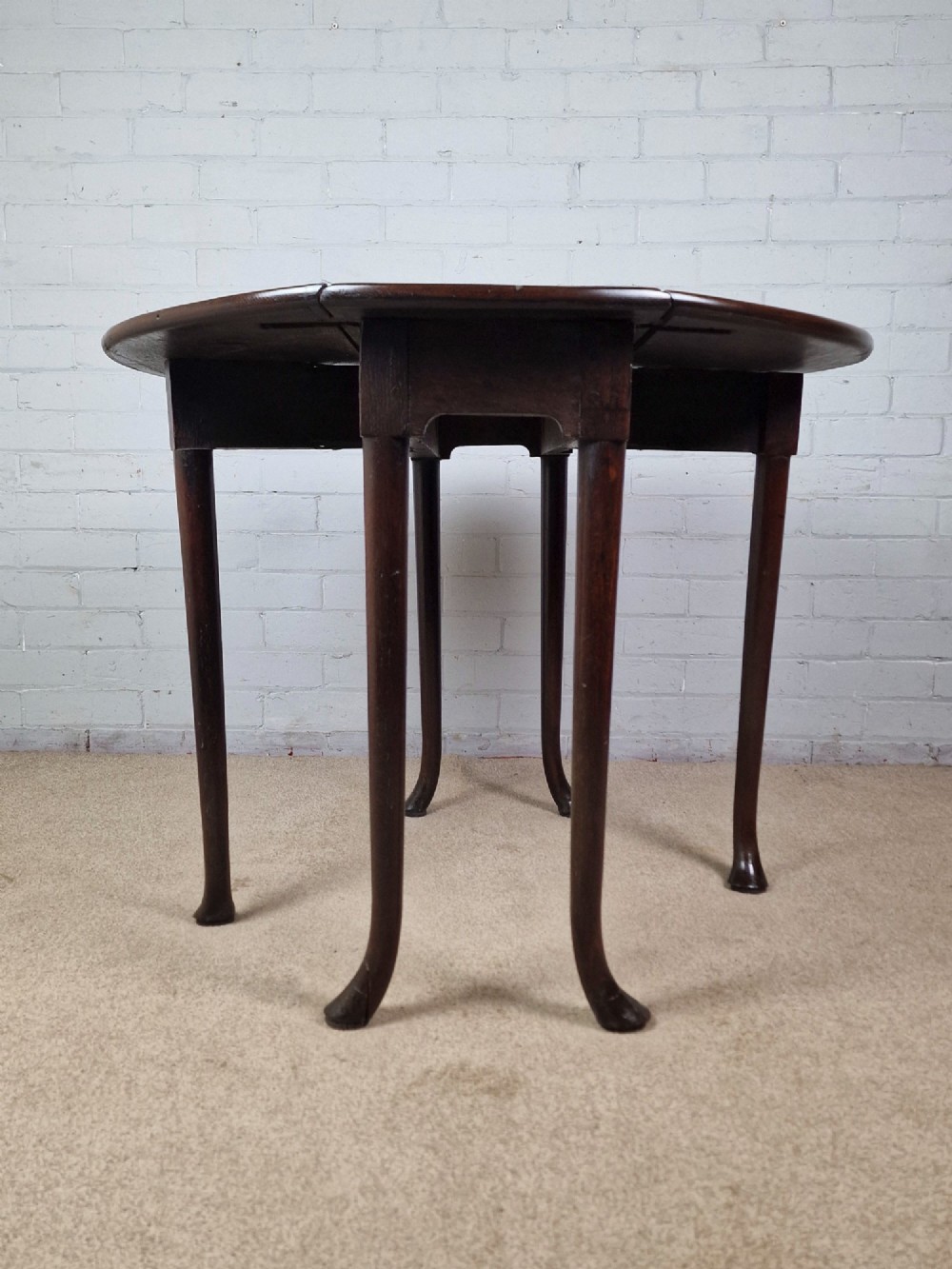 An 18th-century Georgian dark oak gateleg table with hinged leaves and slender tapered legs ending in pad feet. View IX