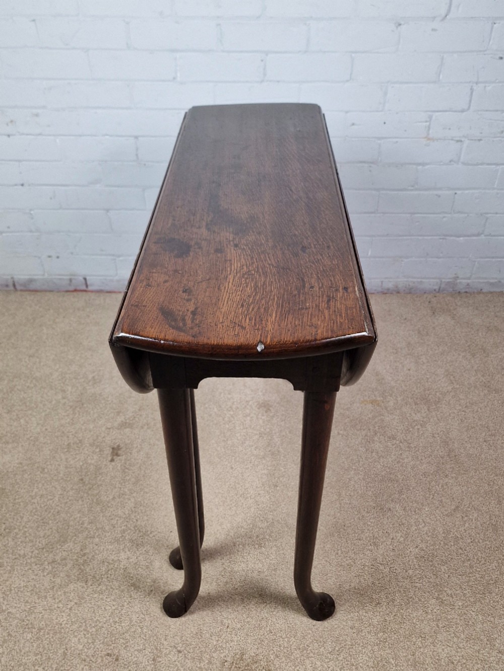 An 18th-century Georgian dark oak gateleg table with hinged leaves and slender tapered legs ending in pad feet. View XI