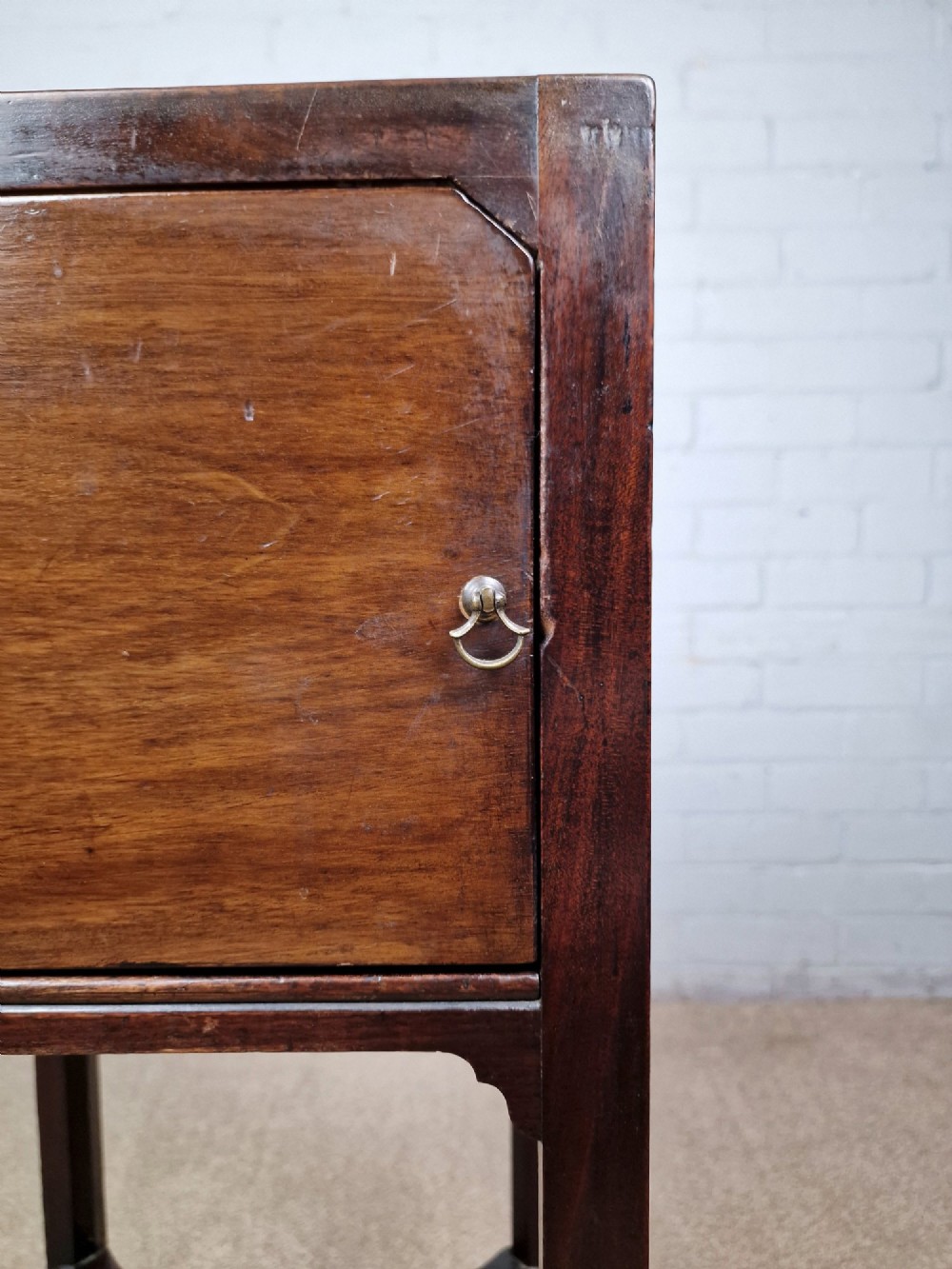 A tall Georgian dark mahogany bedside cabinet with a single door cupboard, straight legs, and an arched lower X-stretcher shelf. View IV