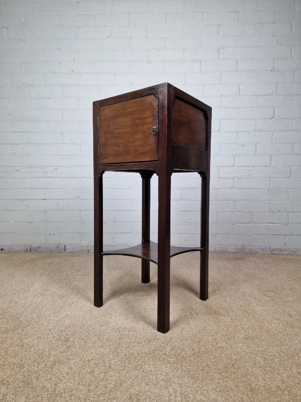 A tall Georgian dark mahogany bedside cabinet with a single door cupboard, straight legs, and an arched lower X-stretcher shelf. View V