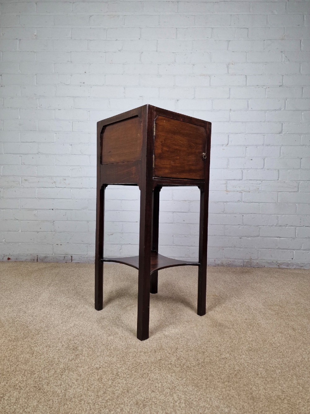 A tall Georgian dark mahogany bedside cabinet with a single door cupboard, straight legs, and an arched lower X-stretcher shelf. View VI