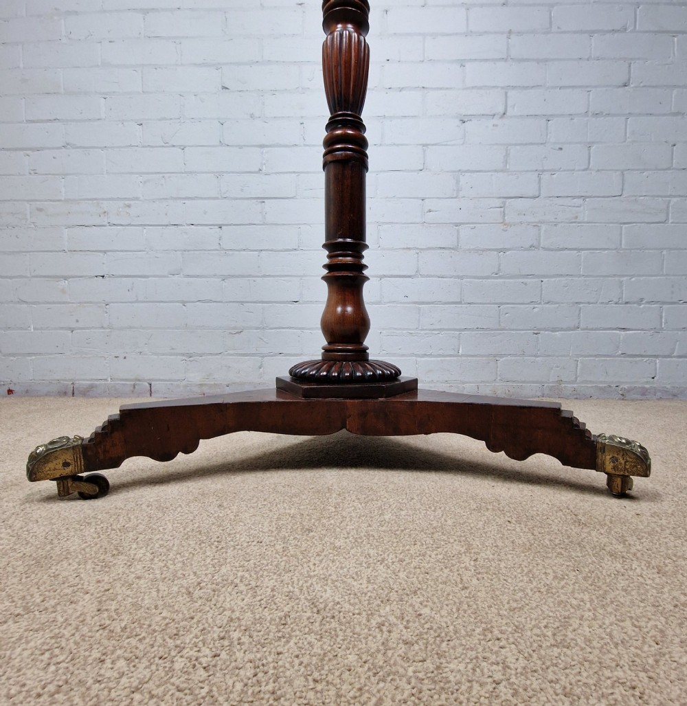 A tall late Georgian mahogany coat stand featuring turned and reeded central pillars, curved hanging hooks, and a splayed tripod base with brass castors. View V
