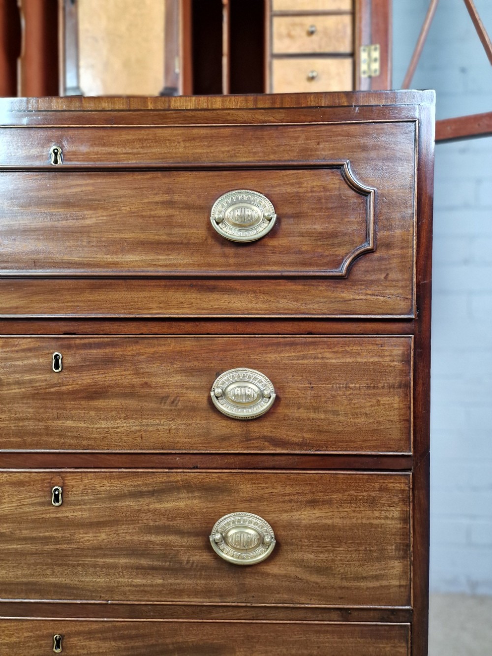 A George III mahogany secretaire bookcase featuring geometric astragal glazed upper doors above a lower chest of drawers with brass drop handles and bracket feet. View XI