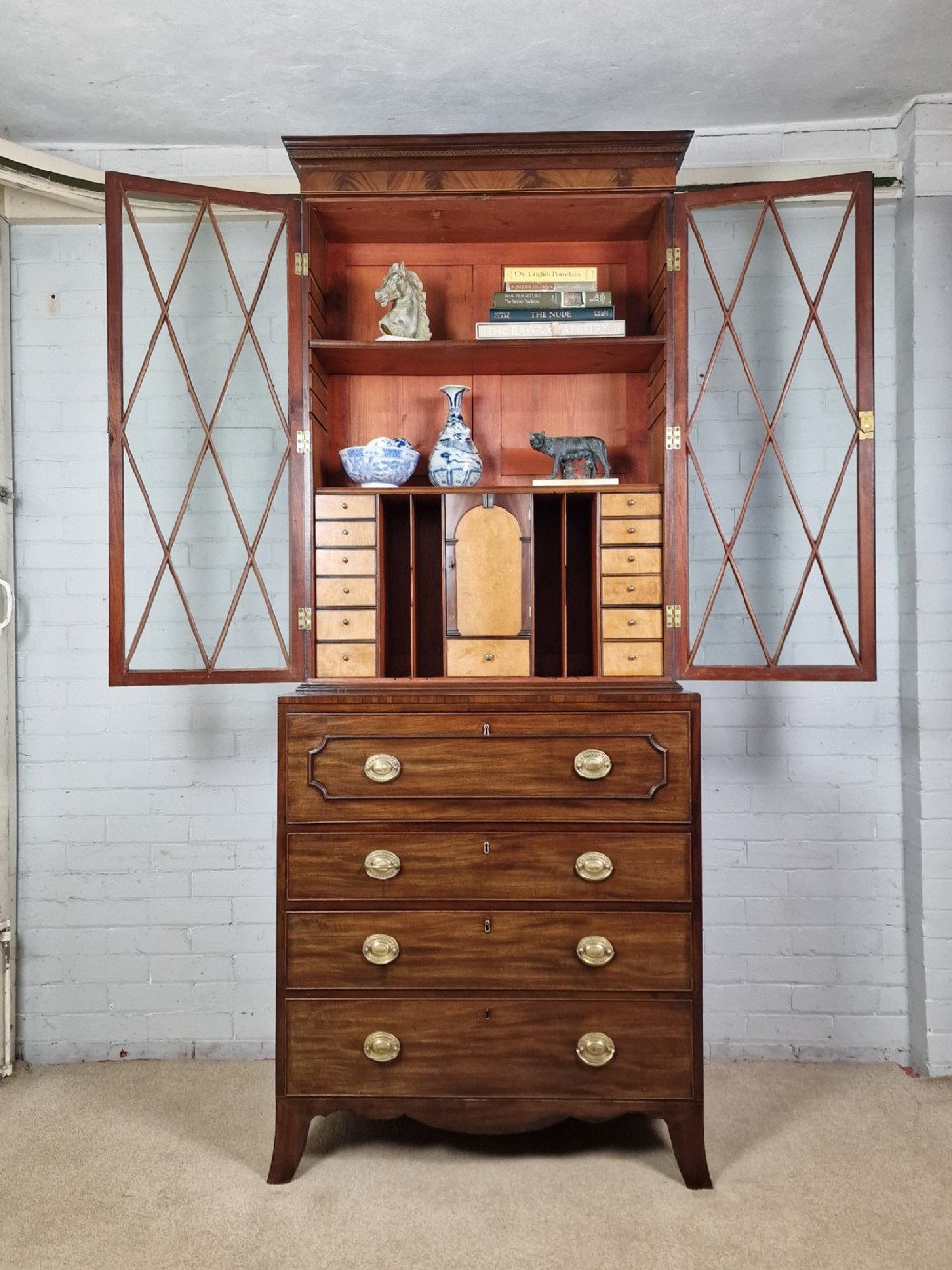 A George III mahogany secretaire bookcase featuring geometric astragal glazed upper doors above a lower chest of drawers with brass drop handles and bracket feet. View XIV