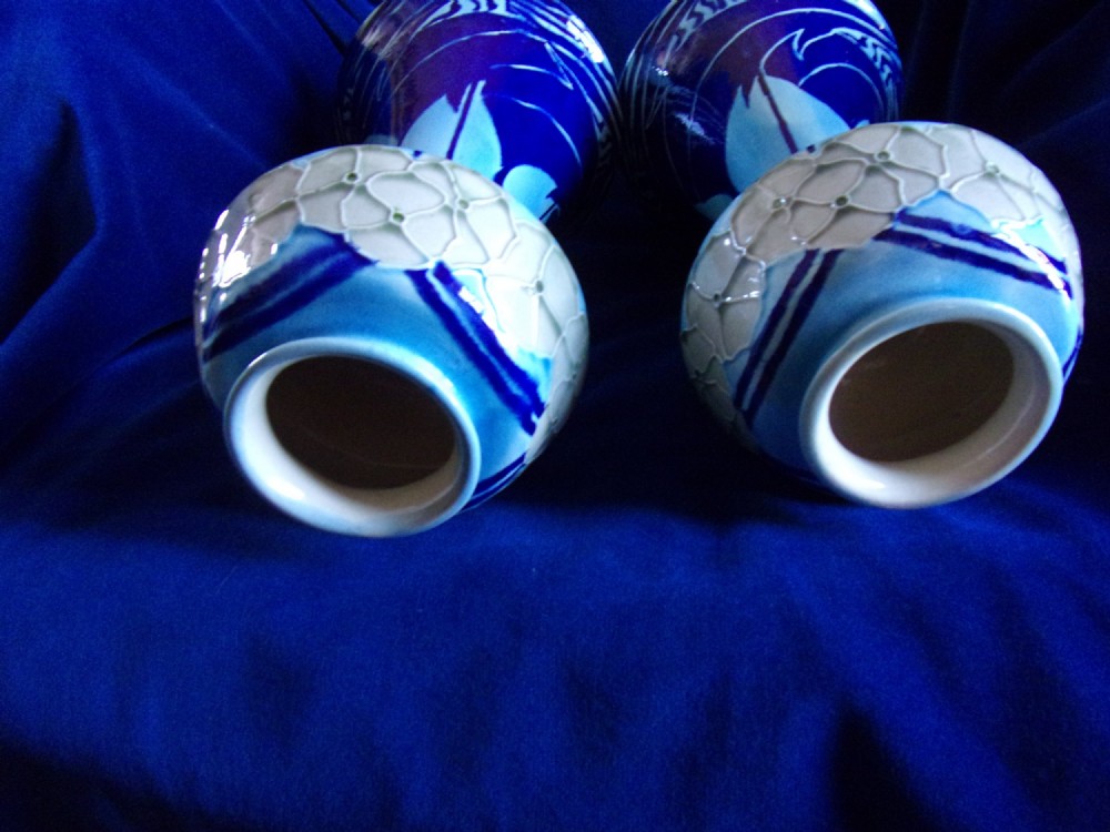 A pair of Edwardian Minton Secessionist earthenware vases with flared bases and bulbous rims, decorated with tube-lined floral and graphic wave motifs in shades of cobalt and sky blue. View III