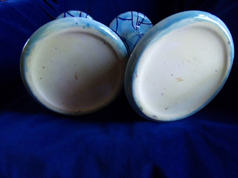 A pair of Edwardian Minton Secessionist earthenware vases with flared bases and bulbous rims, decorated with tube-lined floral and graphic wave motifs in shades of cobalt and sky blue. View IV