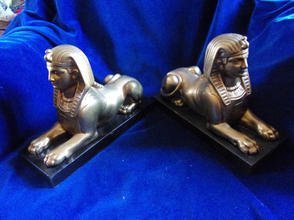 A pair of late 19th-century gilt bronze sphinxes wearing nemes headcloths, mounted on rectangular black marble bases.