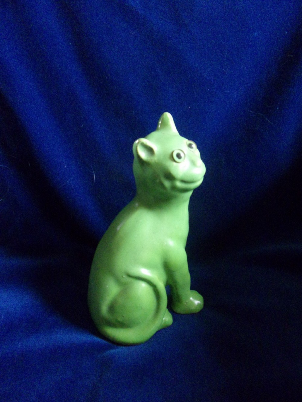 A seated French Art Deco ceramic cat figurine glazed in bright green featuring inset glass eyes.