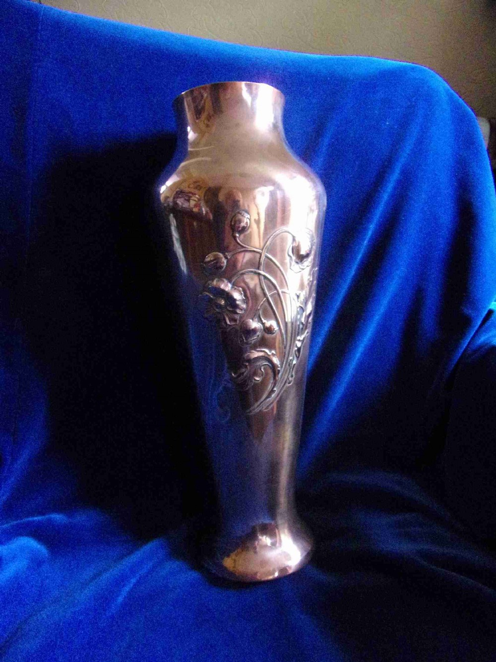 A tall French Art Nouveau copper vase featuring raised botanical floral repousse detailing on a flared body.