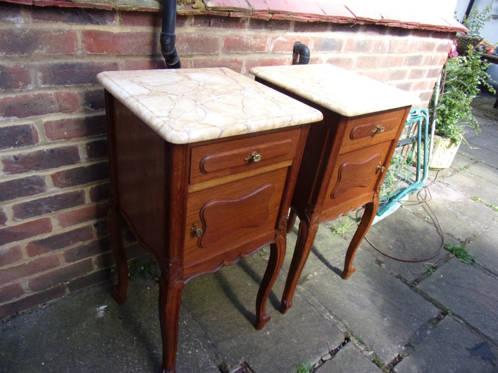 A pair of French oak bedside cabinets featuring mottled beige marble tops, single drawers, cupboard doors with carved raised panels, and slender cabriole legs. View II