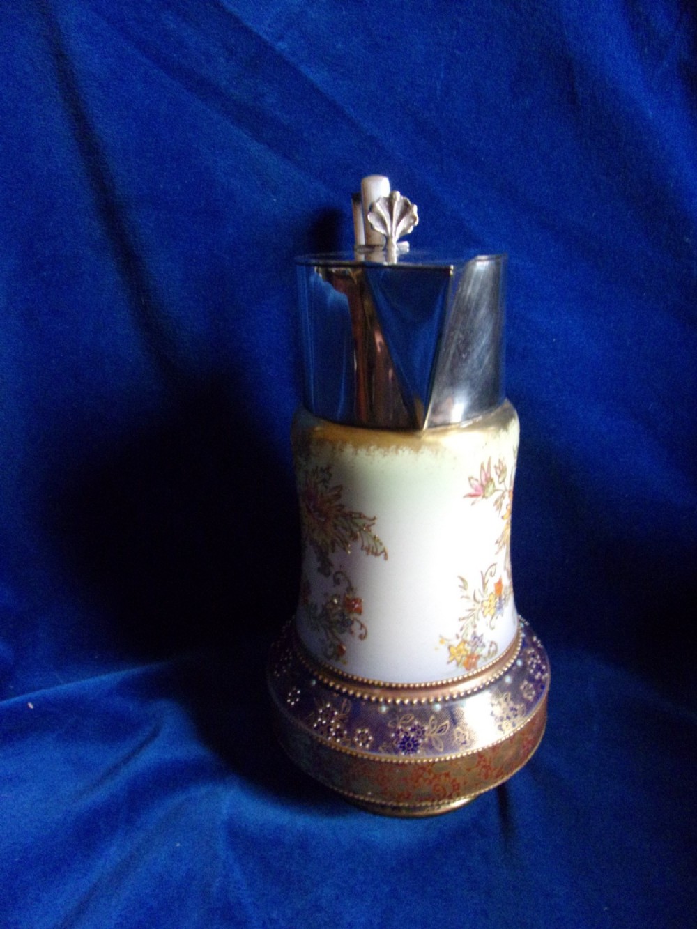 An antique Carlton Ware ceramic claret jug featuring floral enamel detailing and a polished silver-plated neck, lid, and geometric handle. View II