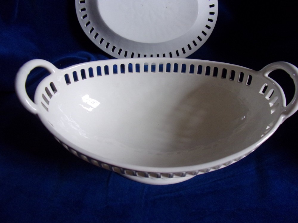 A cream-coloured glazed earthenware basket featuring pierced lattice rims, twin side handles, and a matching reticulated stand. View IV