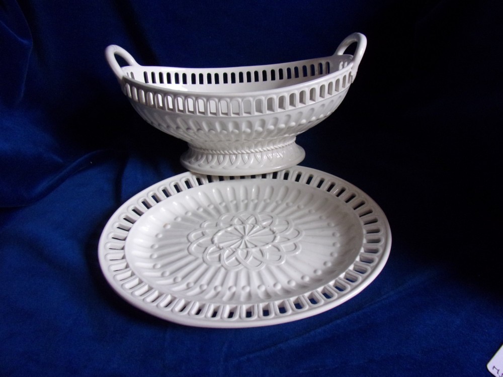 A cream-coloured glazed earthenware basket featuring pierced lattice rims, twin side handles, and a matching reticulated stand. View VII