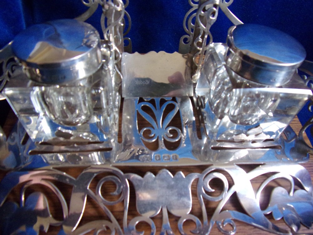 An Edwardian fretted silver standish featuring two glass inkwells mounted on a rectangular carved oak base. View III