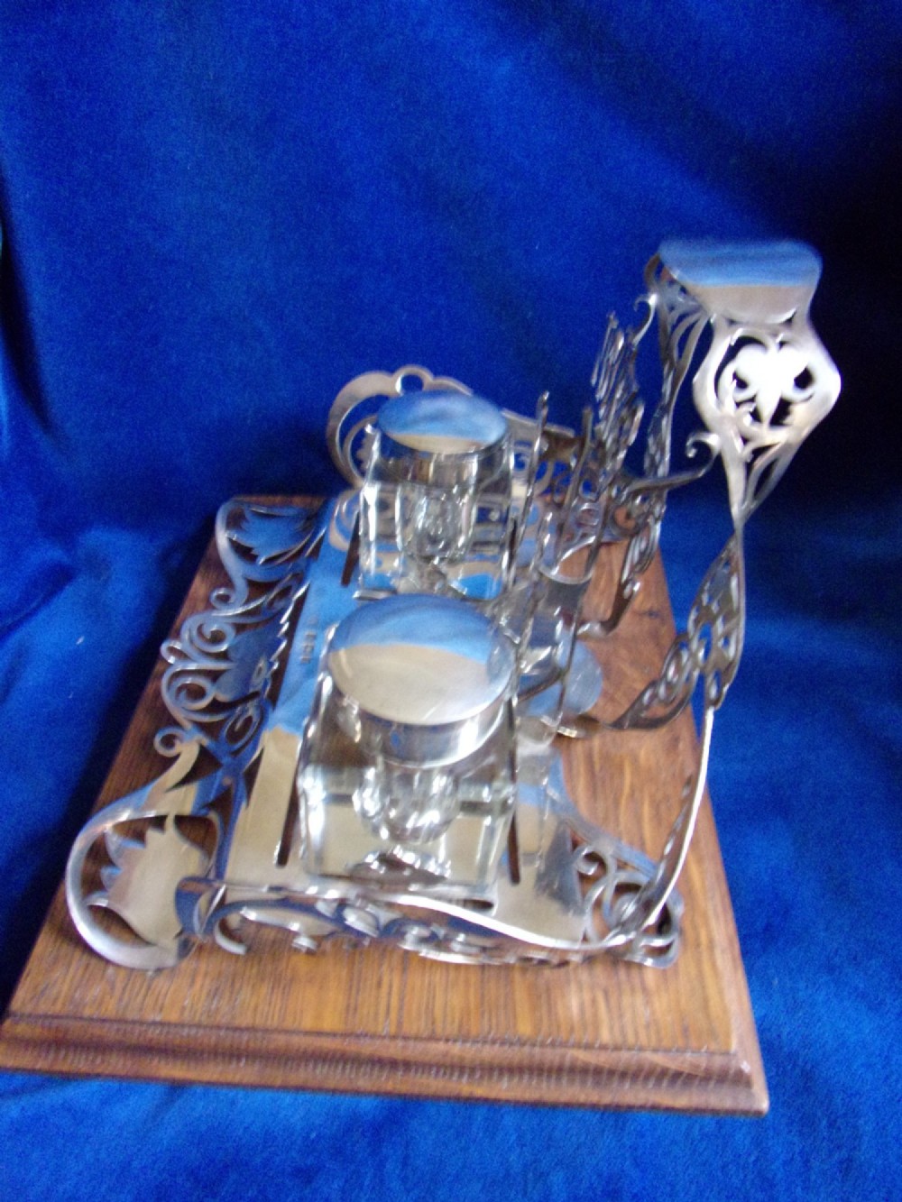 An Edwardian fretted silver standish featuring two glass inkwells mounted on a rectangular carved oak base. View VII