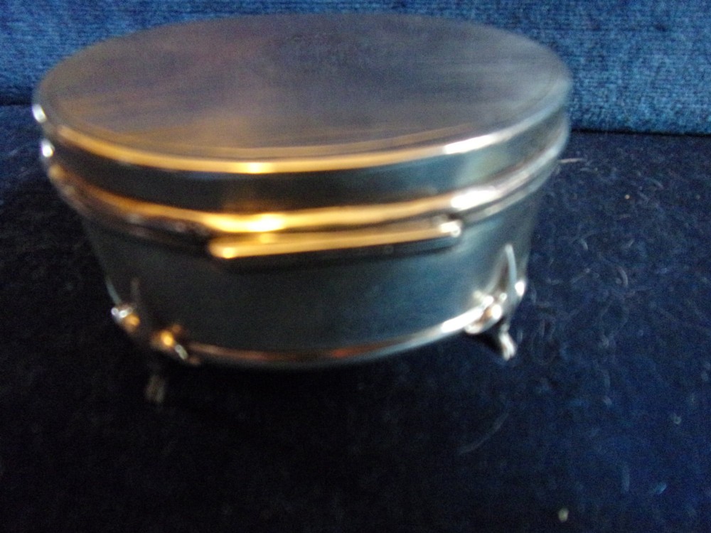 An oval sterling silver trinket box with a smooth polished lid resting on four slender cabriole feet. View II