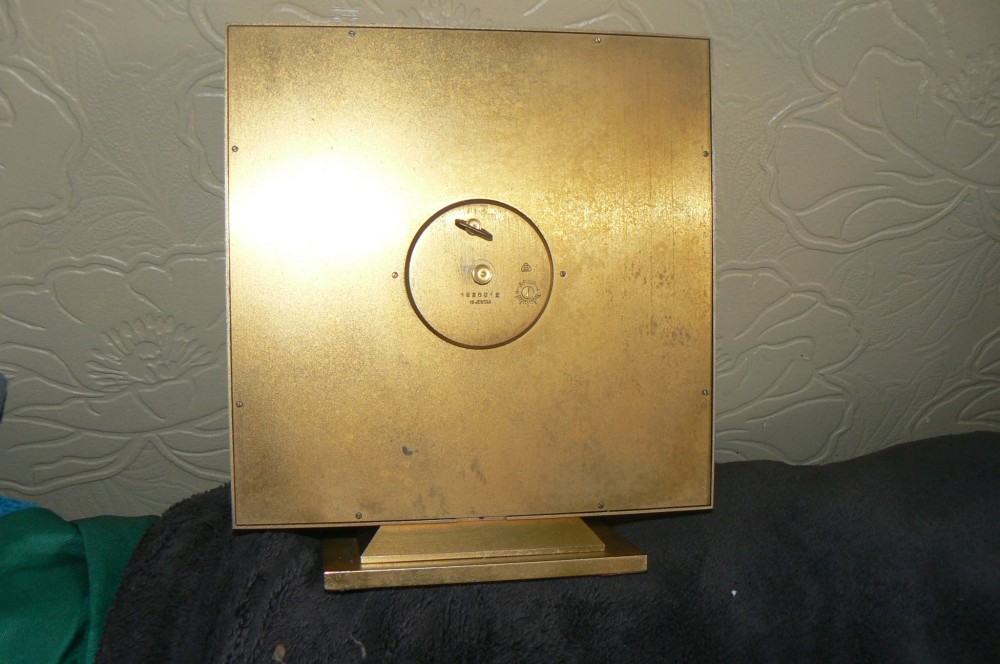 A square Art Deco style Swiss Imhof mantel clock featuring a gilt bronze frame, a dark red dial face, and a circular gold chapter ring with Roman numerals. View III