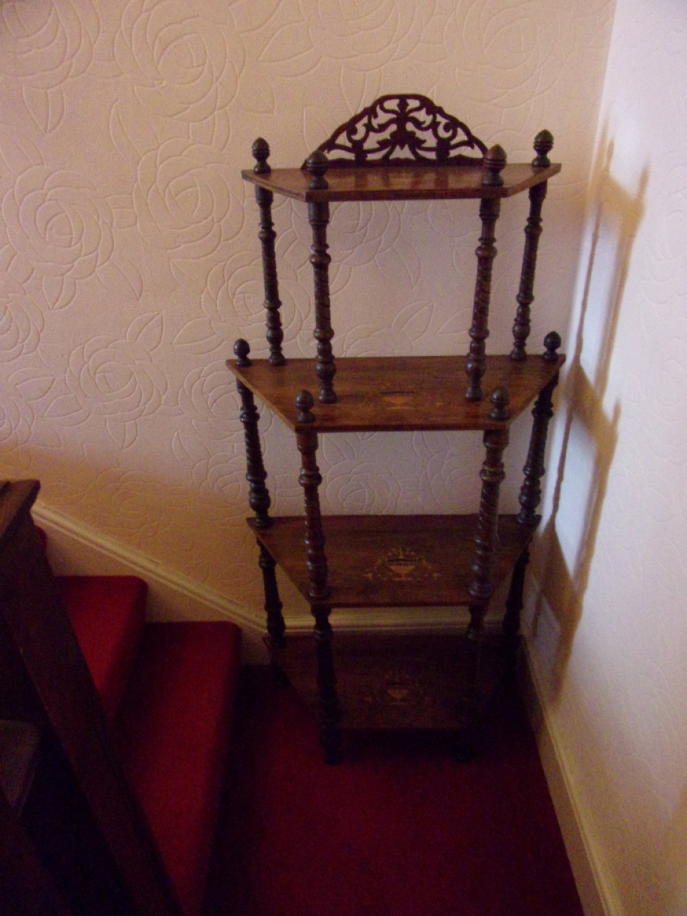A Victorian walnut tiered whatnot stand featuring four tiers with satinwood urn inlay, turned column supports, and a pierced decorative gallery crest.