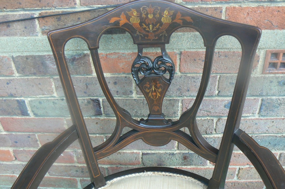 An Edwardian dark mahogany elbow chair featuring inlaid wood detail on the backrest, curved armrests, and a light beige upholstered seat. View II