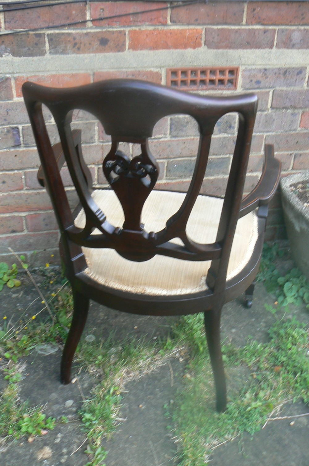 An Edwardian dark mahogany elbow chair featuring inlaid wood detail on the backrest, curved armrests, and a light beige upholstered seat. View III