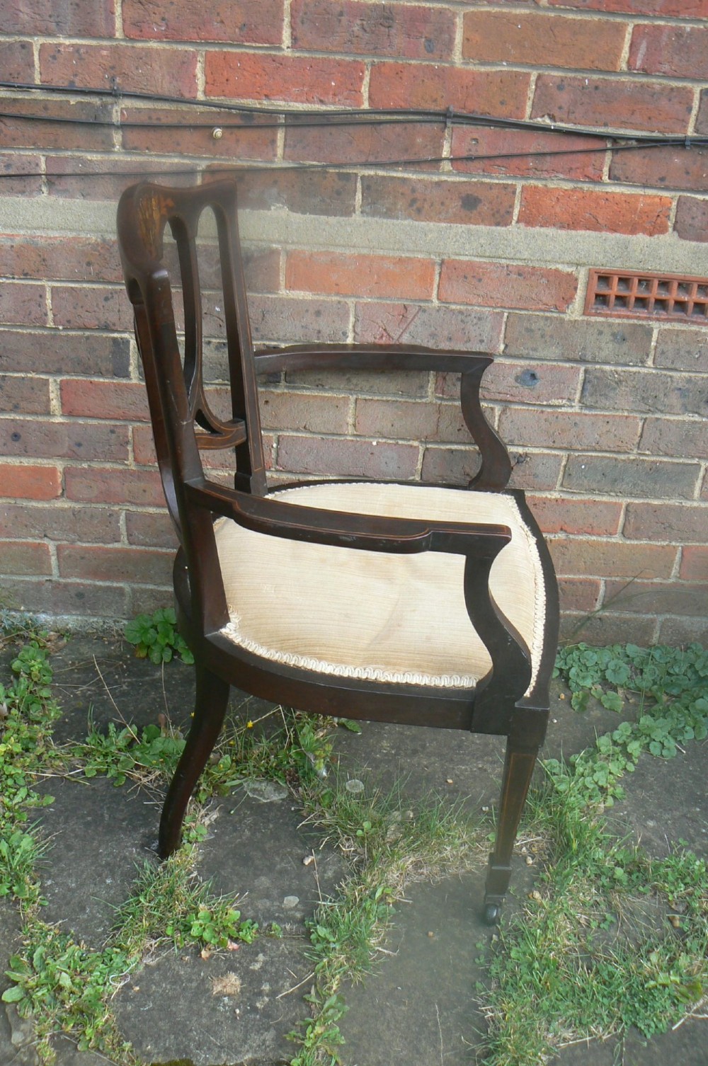 An Edwardian dark mahogany elbow chair featuring inlaid wood detail on the backrest, curved armrests, and a light beige upholstered seat. View IV