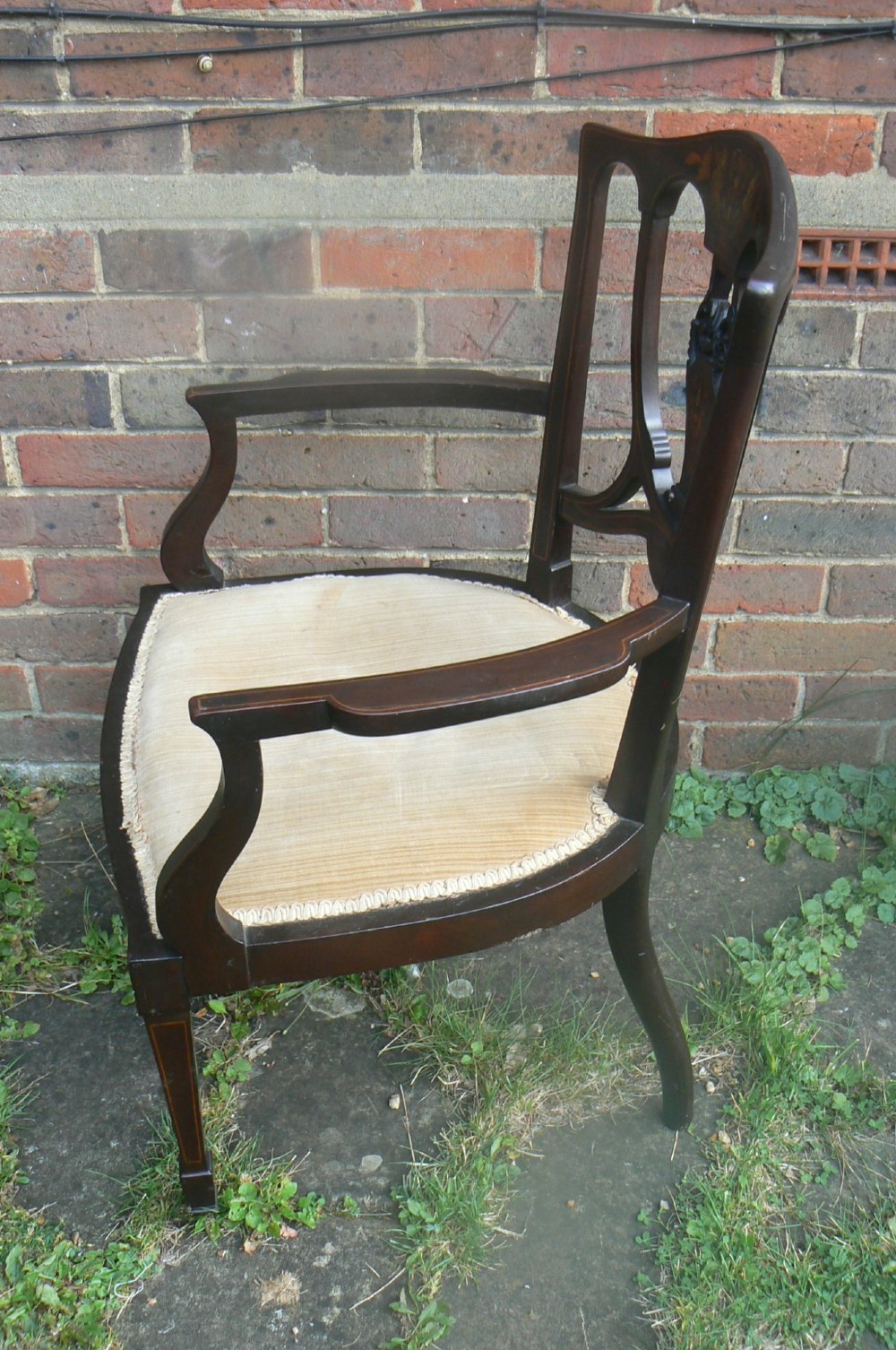 An Edwardian dark mahogany elbow chair featuring inlaid wood detail on the backrest, curved armrests, and a light beige upholstered seat. View V