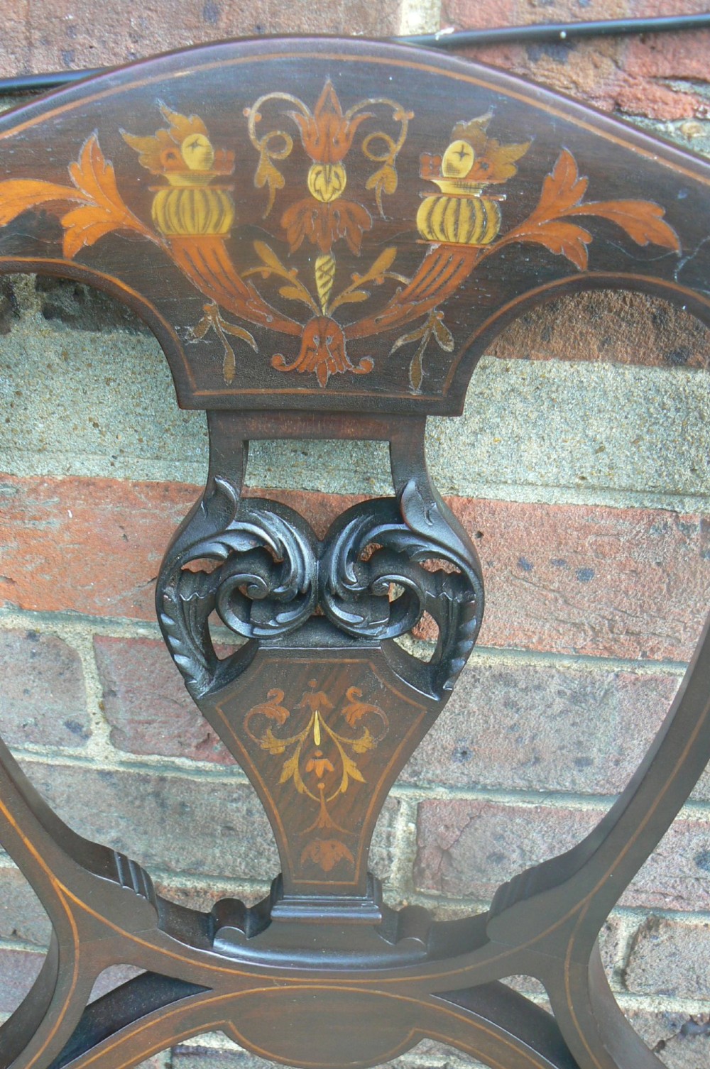 An Edwardian dark mahogany elbow chair featuring inlaid wood detail on the backrest, curved armrests, and a light beige upholstered seat. View VI