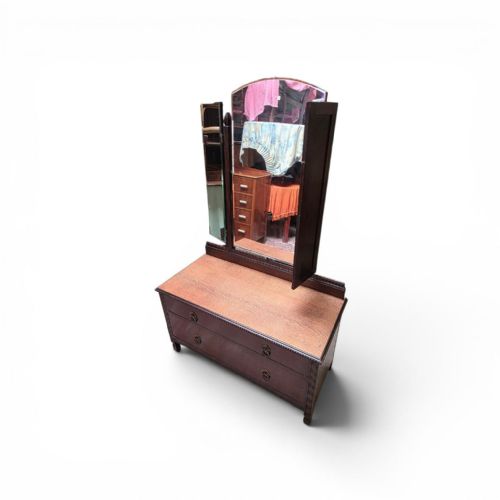 fig 1. A dark oak dressing chest featuring two wide drawers, a natural wood top surface, and an attached folding triple mirror.