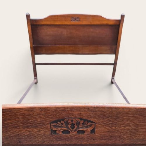 fig 2. A solid oak small double bed frame featuring a panelled headboard and footboard with central carved motifs.