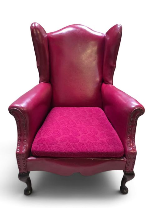 fig 2. A pair of 1930s burgundy leather wingback armchairs featuring patterned fabric seat cushions, studded trim, and dark timber cabriole legs.