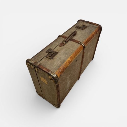 fig 2. A 1930s British Everwear travel trunk covered in grey fabric with wood banding, metal corner caps, and a central leather handle.