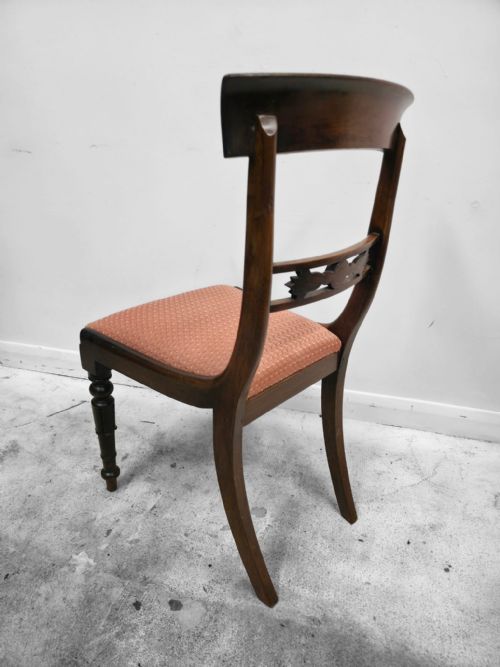 fig 1. A pair of antique mahogany dining chairs featuring curved top rails, carved central back splats, turned front legs, and peach fabric upholstered seats.
