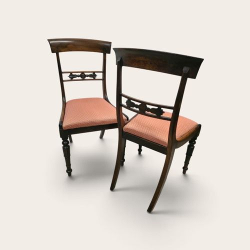 fig 2. A pair of antique mahogany dining chairs featuring curved top rails, carved central back splats, turned front legs, and peach fabric upholstered seats.