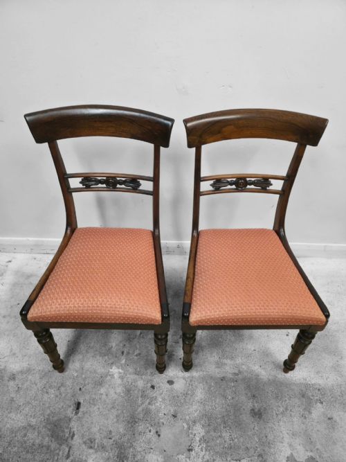 fig 3. A pair of antique mahogany dining chairs featuring curved top rails, carved central back splats, turned front legs, and peach fabric upholstered seats.