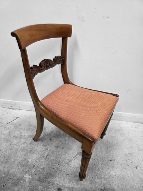 fig 1. A pair of late Regency mahogany dining chairs featuring carved back rails, turned fluted legs, and patterned rose pink upholstered seats.