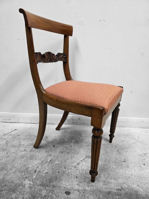 fig 3. A pair of late Regency mahogany dining chairs featuring carved back rails, turned fluted legs, and patterned rose pink upholstered seats.