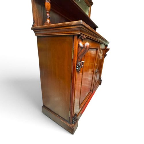 fig 2. A late Victorian mahogany sideboard featuring a raised upper shelf with a rectangular mirror back over a two-door cupboard base flanked by carved corbels.
