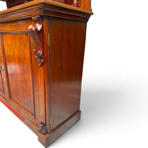 fig 3. A late Victorian mahogany sideboard featuring a raised upper shelf with a rectangular mirror back over a two-door cupboard base flanked by carved corbels.