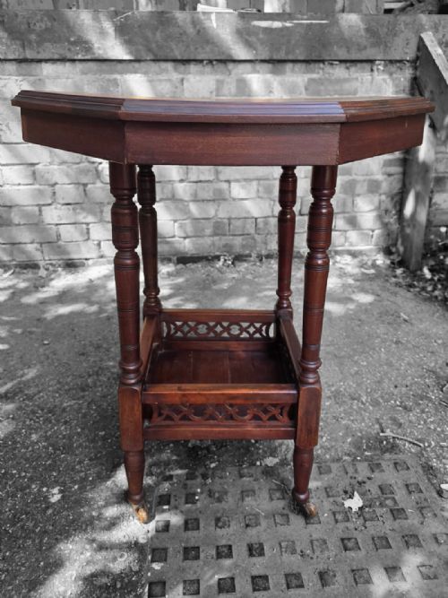 fig 1. A late Victorian octagonal wooden side table featuring turned legs and a square lower shelf with pierced fretwork sides.