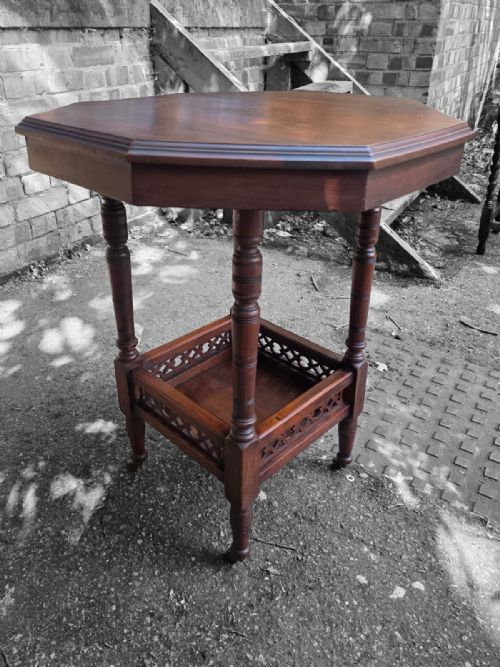 fig 2. A late Victorian octagonal wooden side table featuring turned legs and a square lower shelf with pierced fretwork sides.
