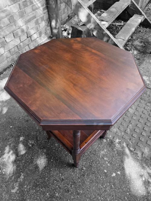 fig 3. A late Victorian octagonal wooden side table featuring turned legs and a square lower shelf with pierced fretwork sides.