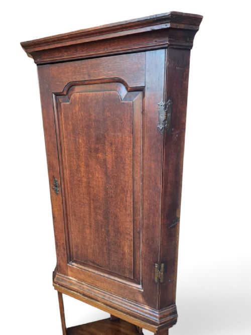 fig 1. A late Victorian English oak corner cupboard featuring a fielded panel door above an open two-tiered stand.
