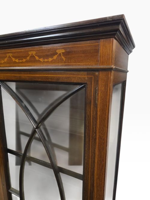 fig 2. An Edwardian mahogany display cabinet featuring inlaid marquetry details, astragal glazed twin doors, and an open lower undertier shelf.