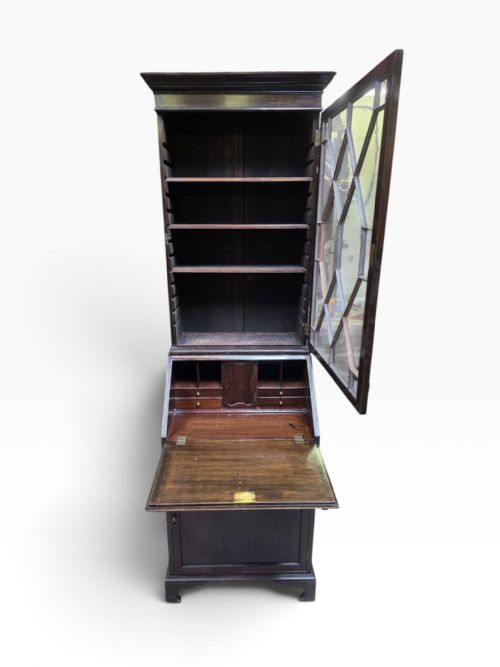 fig 3. An Edwardian dark mahogany bureau bookcase featuring an upper cabinet with astragal glazed doors, a slant-front writing slope, and a lower door cupboard on bracket feet.