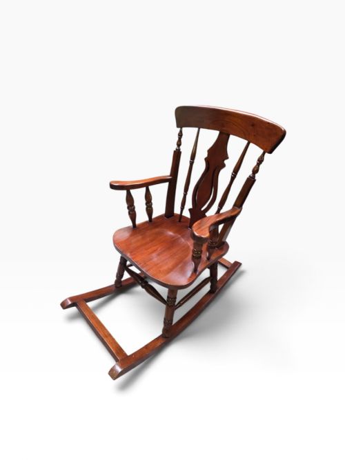 fig 2. An antique Victorian mahogany Windsor rocking chair featuring turned spindles, a shaped central splat, armrests, and wooden rocker runners.