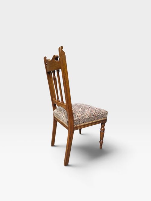 fig 1. A set of six Edwardian oak dining chairs featuring carved cresting rails, vertical splat backs, turned front legs, and patterned fabric seats.