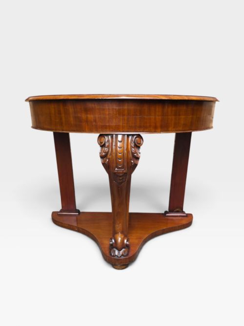 fig 1. A William IV mahogany demi-lune console table featuring a semicircular fold-over top, a central carved scroll leg, and a shaped plinth base.