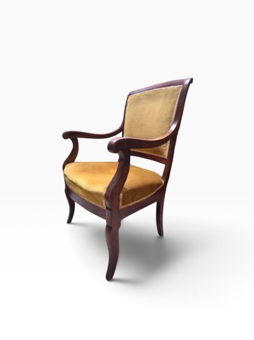 fig 2. A late Victorian mahogany carver armchair featuring curved armrests and mustard yellow velvet upholstery on the seat and backrest.