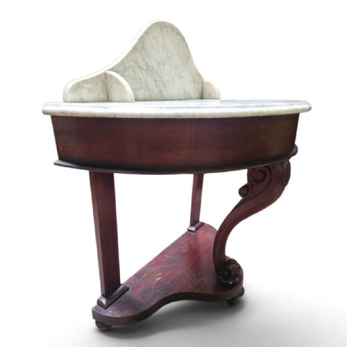 fig 3. A Victorian mahogany washstand featuring a curved white marble top with a splashback and a single carved scroll front leg.