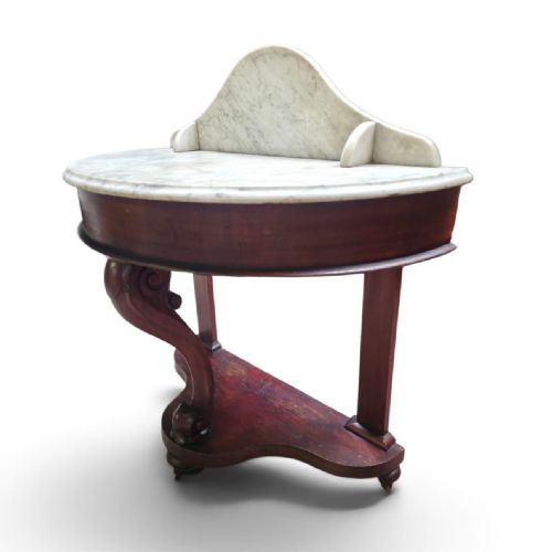 fig 4. A Victorian mahogany washstand featuring a curved white marble top with a splashback and a single carved scroll front leg.